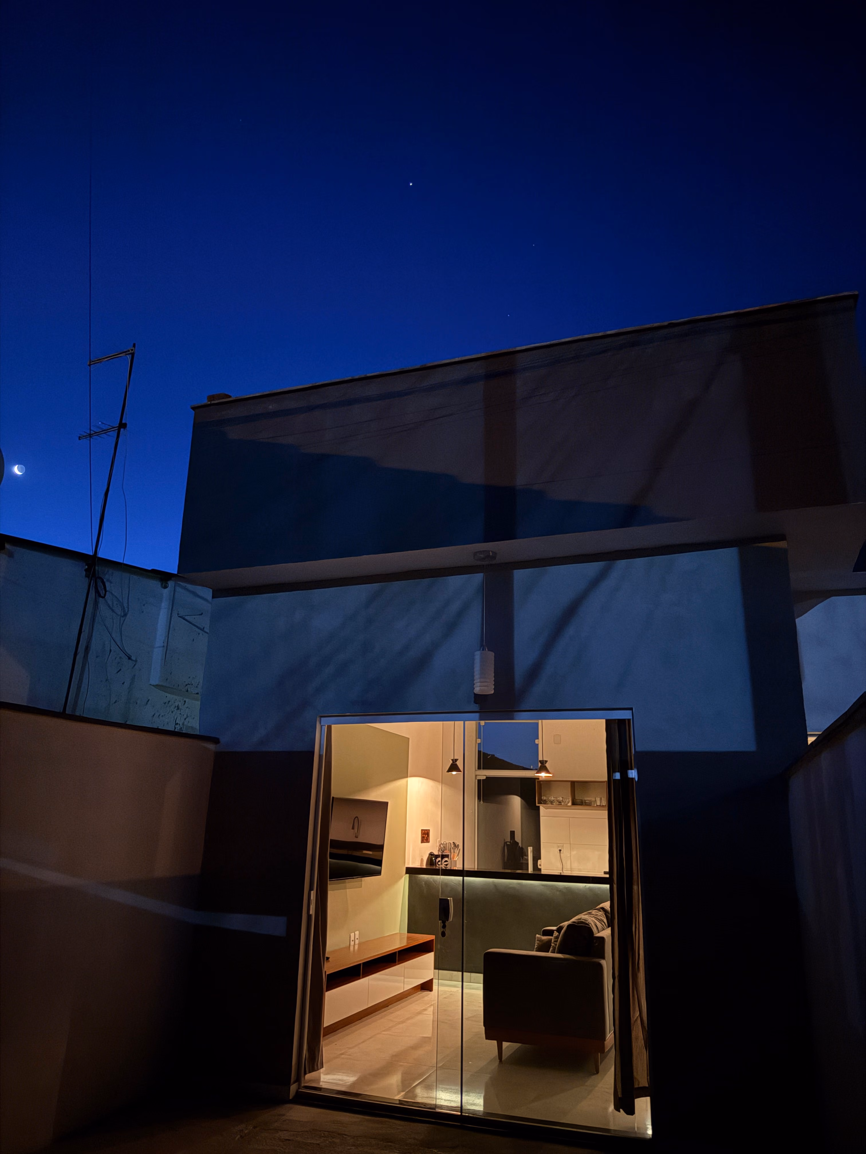 Vista da casa ao entardecer, com a sala iluminada