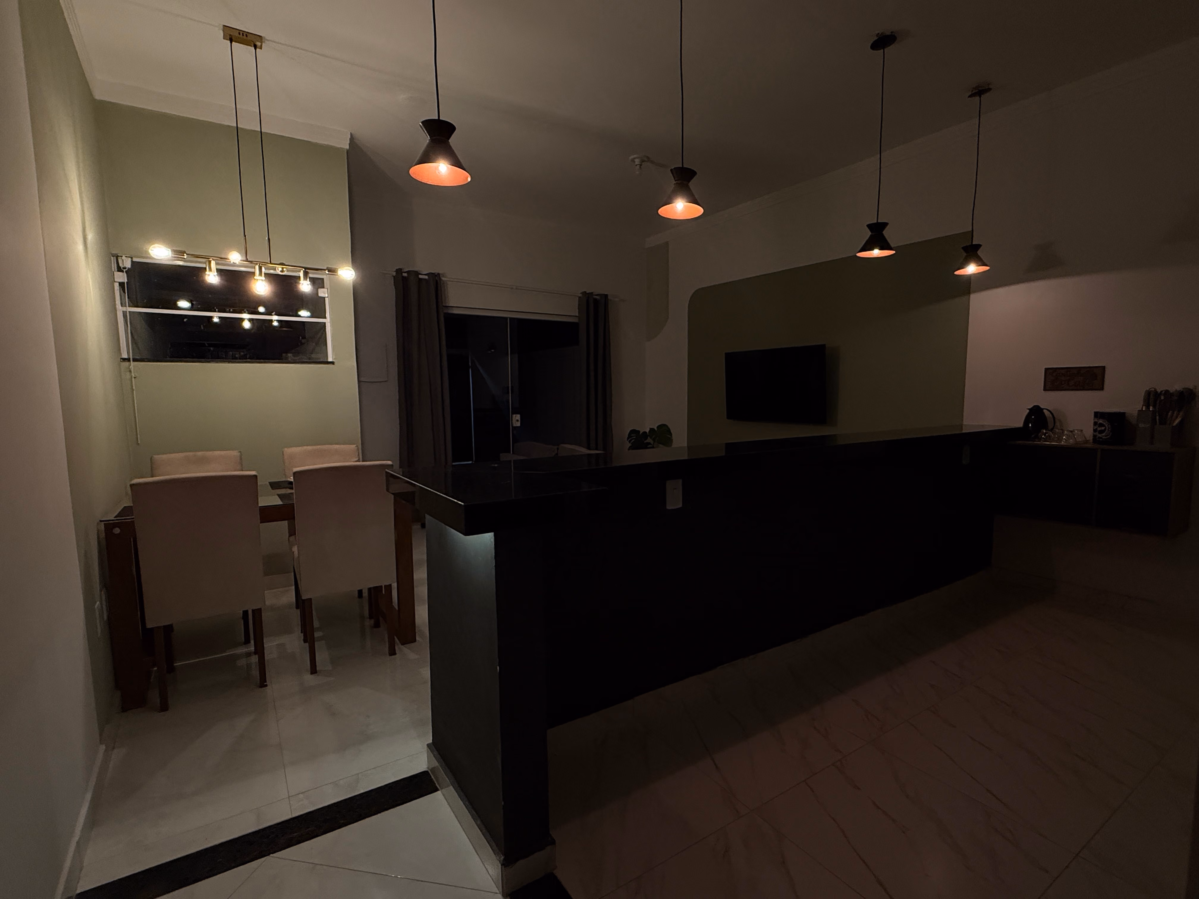 Sala, jantar e cozinha integrados à noite, com luz quente